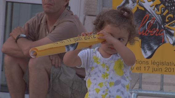  Une petite fille semblant regarder l’avenir à travers l'affiche du candidat Paul Quastana aux élections législatives de 2012